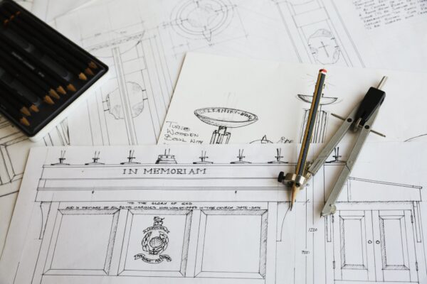 Close up of design drawings for furniture and a compass.